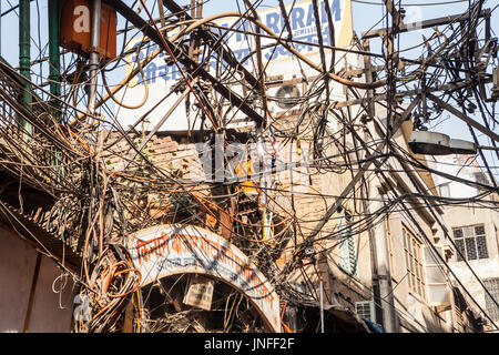 A tangle of utility wires and cables above the streets in Chandni Chowk, a wholesale market in Old Delhi, India. Stock Photo