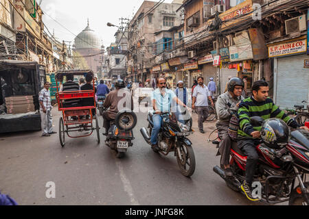 A street scene in Chandni Chowk, one of the oldest and busiest markets in Delhi, India. The dome of Jama Masjid, a mosque rises in the background. Stock Photo