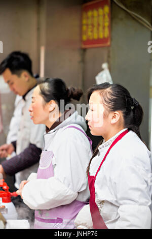 Chinese three salesmen serving food on traditional food market. Wangfujing, Dongcheng District, Beijing, China, 5 April 2016 Stock Photo