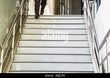 Low section shot of a man in black slacks walking up the stairs Stock Photo