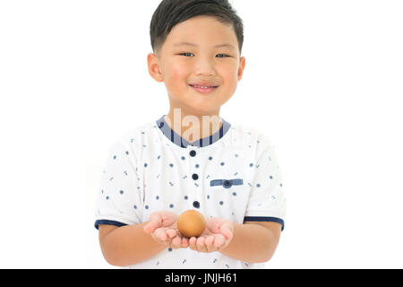 Little boy holding hen egg in hand isolated on white background Stock Photo