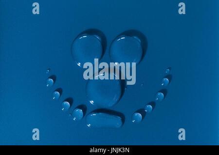 Smiling face made of waterdrops on a blue background Stock Photo