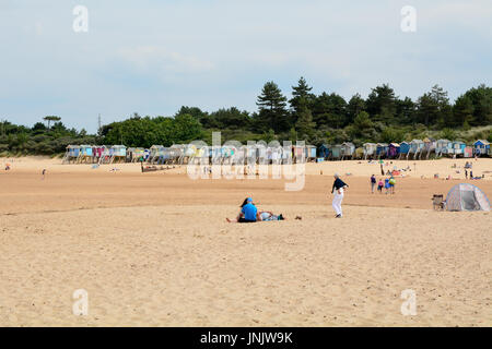 Summer beach scene with the famous painted wooden beach huts at Wells-next-the-sea Norfolk England Stock Photo