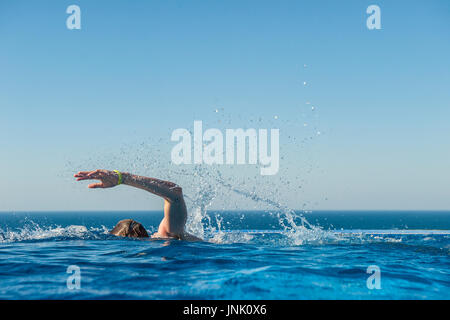 A teenage boy trains in an infinity pool Stock Photo