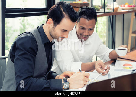 Two young Multiethnic businessman working on table In coffee shop. Stock Photo