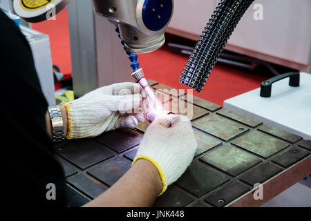 Worker using repair mold and die part by Laser welding machine in factory. Stock Photo