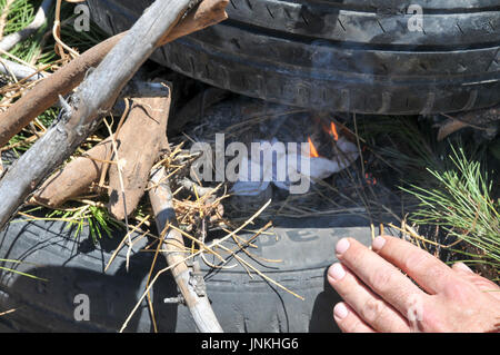 How to start a fire with old tires and branches. a set of 5 images Stock Photo