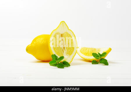 whole and sliced lemons on white wooden background Stock Photo
