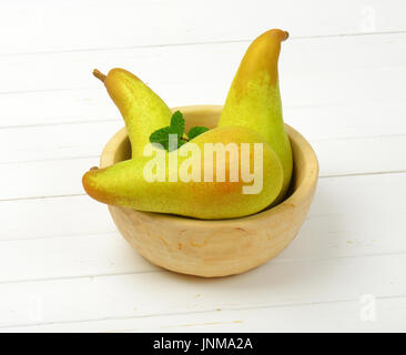 three yellow pears in wooden bowl Stock Photo