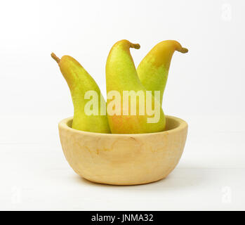 three yellow pears in wooden bowl Stock Photo