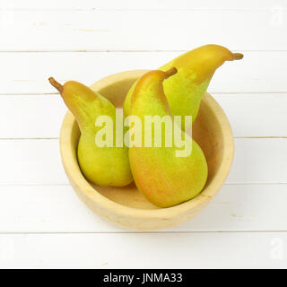 three yellow pears in wooden bowl Stock Photo