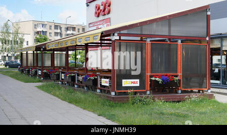 VILNIUS, LITHUANIA - JULY 06, 2017:  A wooden pavilion with flowers and tables near PicaMax pizzeria. Nearby there is a large store of the trade brand Stock Photo