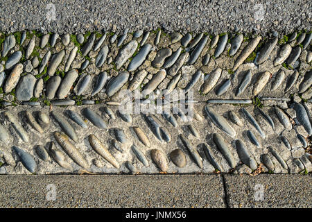 Roadside gutter lined with rounded stones, Monein, France. Stock Photo