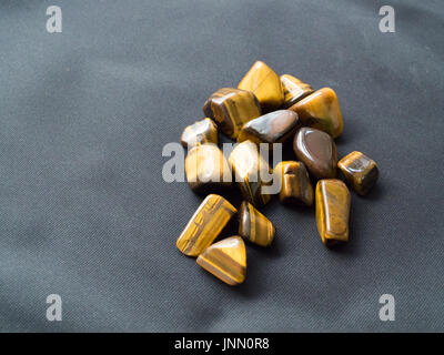 Tumbled Eye of the tiger stones from top on black cloth for crystal therapy treatments and reiki Stock Photo