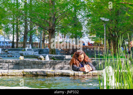 London, UK - May 10, 2017 - A woman taking pictures in Jubilee Park, a landscaped space in Canary Wharf