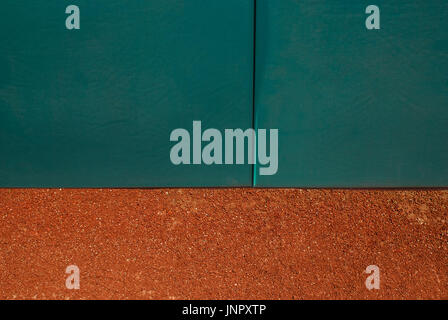 Green baseball home run wall with track dirt. Stock Photo