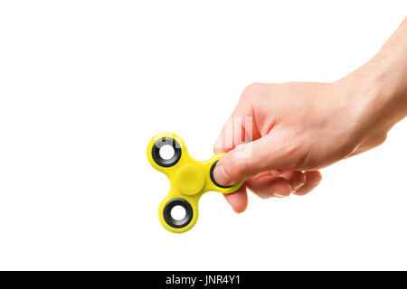 A man's hand holds a yellow fidget spinner Stock Photo