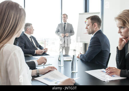 Group of business people at meeting watching presentation of reports in diagrams and graphs at flip chart in offfice Stock Photo