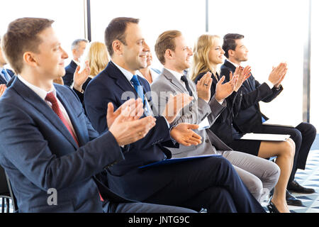 Audience of happy business people sitting at training room, conference hall, applauding to speaker Stock Photo