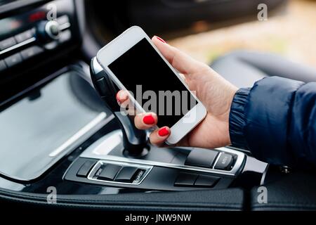 Woman using white smartphone in car. Modern car interior Stock Photo