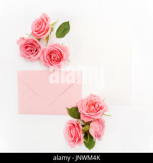 Envelop with white card and rose background. Top view. Flat lay Stock Photo