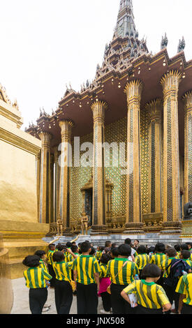 Bangkok, Thailand - February 18, 2015: Group of schoolchildren in yellow and green striped uniform visiting the Grand Palace in Bangkok. Stock Photo