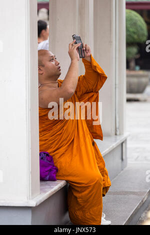 Bangkok, Thailand - February 18, 2015: Buddhist monk taking photos with a smartphone at the Grand Palace in Bangkok. Stock Photo