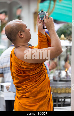 Bangkok, Thailand - February 18, 2015: Buddhist monk taking photos with a smartphone at the Grand Palace in Bangkok. Stock Photo