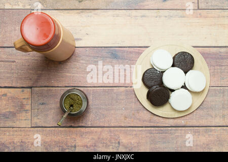 top view of mate, thermos and alfajores on wooden table
