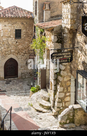 Eze, Alpes-Maritimes, France - October 11, 2015: Street in Eze with artist's studio sign. Eze is a quaint, well-preserved, old village on the Mediterranean in the Alpes-Maritimes department of France, popular with tourists. Stock Photo