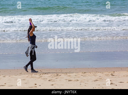 Bournemouth, Dorset, UK. 31st July, 2017. UK weather: after a weekend of mixed weather, a warm sunny start to the new week, as visitors head to the seaside to make the most of the sunshine. Young woman walking along seashore. Credit: Carolyn Jenkins/Alamy Live News Stock Photo