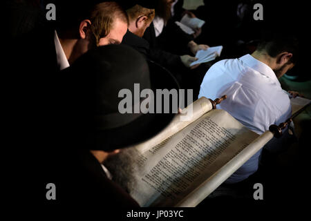 Israel, Jerusalem 31st July. Orthodox Jewish men mourning and reading from the biblical Book of Lamentation on Tisha B'Av feast at the Western Wall in Jerusalem Israel on 31 July 2017. Tisha B'Av is an annual fast day in Judaism, The fast commemorates the destruction of the First and Second Temples in Jerusalem, which occurred about 656 years apart, but on the same date. Accordingly, the day has been called the 'saddest day in Jewish history. Stock Photo