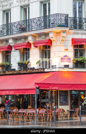 Paris, France - March 2, 2016: Le Saint Germain restaurant cafe with red awnings, early morning with lights still on. Stock Photo