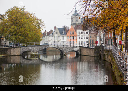 Bruges, Belgium – October 31, 2010: Mother and daughter cycle across bridge in the old part of Bruges in Autumn. Stock Photo