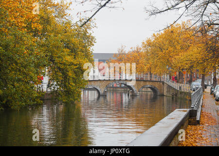 Bruges, Belgium – October 31, 2010: Older couple walking by the canal in Bruges in Autumn. Stock Photo