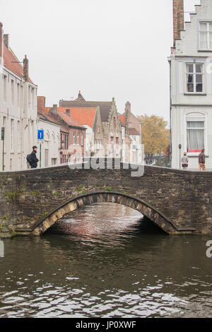 Bruges, Belgium – October 31, 2010: Pedestrians and bridge over canal in Bruges. Stock Photo