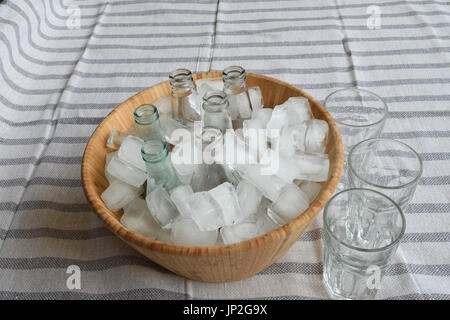 Beverages in bottles on ice in wooden bucket Stock Photo