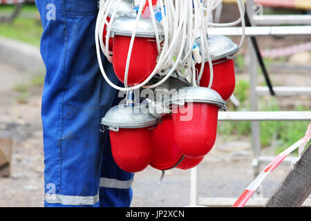 An electrician removes a lot of red warning lights from the fence before dismantling it at the site of the pipeline accident after the work is complet Stock Photo
