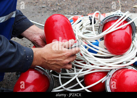 An electrician removes a lot of red warning lights from the fence before dismantling it at the site of the pipeline accident after the work is complet Stock Photo
