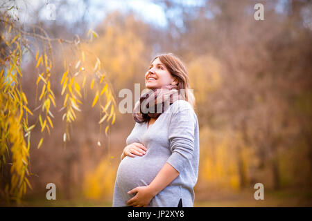 Happy young smiling pregnant woman in autumn park Stock Photo
