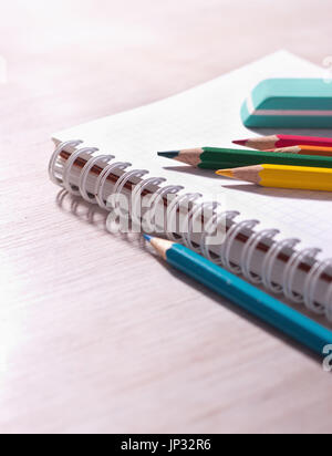 Close up of wooden crayons and eraser on blank note book on wooden desk Stock Photo