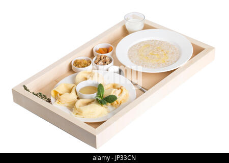Russian pancakes with oatmeal and dried fruits on a wooden tray. Isolated on a white background. Stock Photo