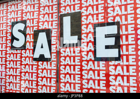 Death of the High Street metaphor / concept - Red and black SALE signs / posters in a shop window. High Street crisis, high street squeeze. Stock Photo