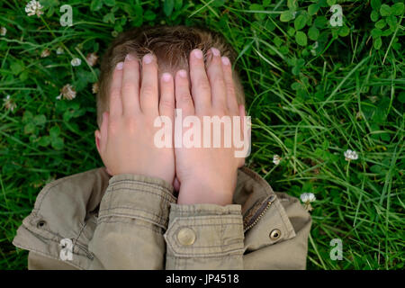 Teenage boy closes his eyes with hands Stock Photo