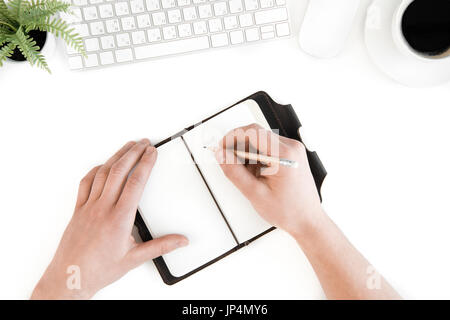top view of person writing in diary at workplace with computer keyboard, isolated on white Stock Photo