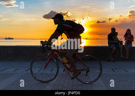 Cyclist at sunset on Manila Bay, Philippines Stock Photo