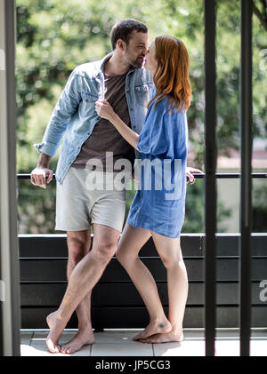 A couple standing on a balcony kissing. Stock Photo