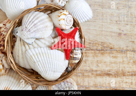 Various seashells in woven basket on rustic background. Top view with copy space Stock Photo