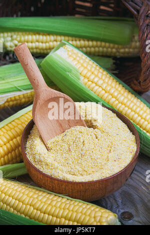 Organic maize flour in wooden bowl with fresh corn Stock Photo