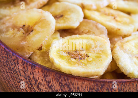 Homemade banana chips (dried and fried banana slices) in wooden bowl Stock Photo